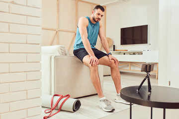 Wall Mural - Handsome young man watching online workout on smartphone