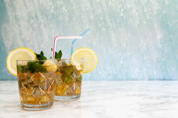 two iced tea glasses with lemon slice on marble