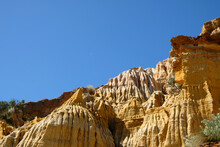 Sandstone Formations On The Coast Contrasted Against A Blue Sky With A Half Moon