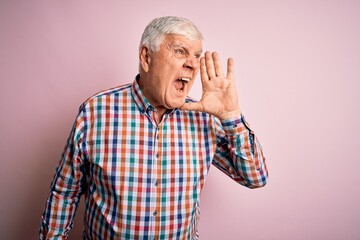 Wall Mural - Senior handsome hoary man wearing casual colorful shirt over isolated pink background shouting and screaming loud to side with hand on mouth. Communication concept.