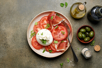Wall Mural - Buratta salad with tomatoes and prosciutto or jamon. Traditional Mediterranean appetizer. Italian Cuisine