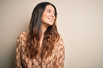 Wall Mural - Young beautiful brunette woman wearing casual t-shirt standing over white background looking away to side with smile on face, natural expression. Laughing confident.