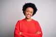 © Krakenimages.com - Young beautiful African American afro woman with curly hair wearing red casual sweater happy face smiling with crossed arms looking at the camera. Positive person.