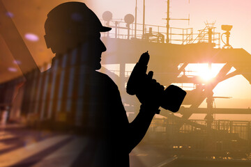 Man works petroleum production platform. Silhouette worker with screwdriver. Concept - crude oil production. Construction of offshore oil platform. Oilman. Oil platform silhouette on sky background