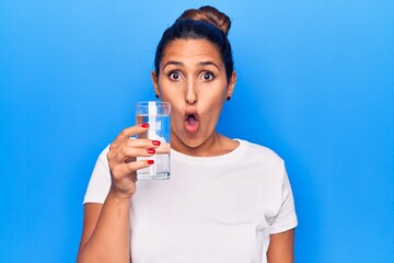 Sticker - Young beautiful brunette woman drinking glass of water scared and amazed with open mouth for surprise, disbelief face