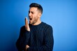 © Krakenimages.com - Young handsome man wearing casual sweater standing over isolated blue background bored yawning tired covering mouth with hand. Restless and sleepiness.