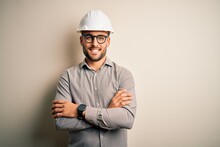 Young Architect Man Wearing Builder Safety Helmet Over Isolated Background Happy Face Smiling With Crossed Arms Looking At The Camera. Positive Person.
