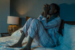 © TheVisualsYouNeed - young sad and depressed black afro American woman on bed at home unhappy and sleepless at night feeling overwhelmed suffering depression problem and insomnia