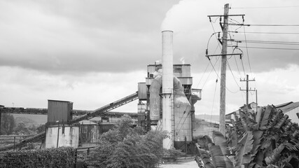 Old factory with chimney and smoke on a cloudy background, monochrome