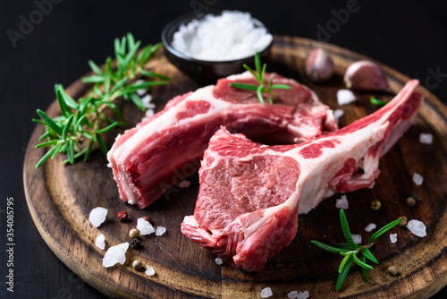 Fotomural Two raw lamb chops on a wooden cutting board with spices on a dark wooden backgr