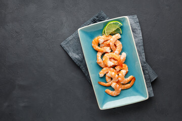 Seafood. Boiled shrimp in a plate on a black background. Top view with copy space.