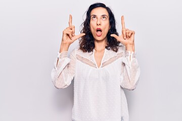 Young beautiful hispanic woman wearing casual clothes amazed and surprised looking up and pointing with fingers and raised arms.