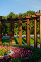 Wall Mural - landscaping using a wooden arch in the garden with flowers and plants, a flowerbed with bright flowers planted according to the pattern