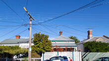 A Row Of Detached Houses In A St Kilda Suburb. A Telegraph Pole Has Many Crossing Over Cables Running Into The Houses On The Street.