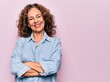 Leinwandbild Motiv Middle age beautiful woman wearing casual denim shirt standing over pink background happy face smiling with crossed arms looking at the camera. Positive person.