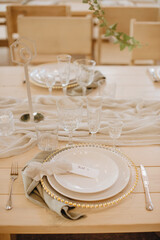 Rustic. Wooden banquet table setting: plates, cutlery, linen napkins, crystal glasses, seating cards with table number