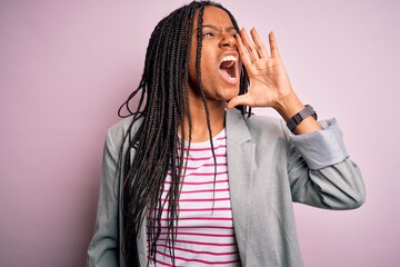 Sticker - Young african american business woman standing over pink isolated background shouting and screaming loud to side with hand on mouth. Communication concept.