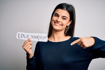 Wall Mural - Young beautiful woman asking for take care of you holding paper with love yourself message with surprise face pointing finger to himself