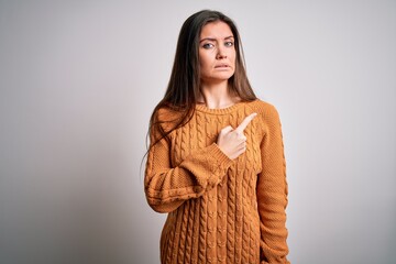 Young beautiful woman with blue eyes wearing casual sweater standing over white background Pointing aside worried and nervous with forefinger, concerned and surprised expression