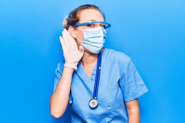 Wall Mural - Young blonde woman wearing doctor uniform and coronavirus protection holding help reminder smiling with hand over ear listening and hearing to rumor or gossip. deafness concept.