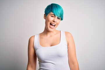 Sticker - Young beautiful woman with blue fashion hair wearing casual t-shirt over white background winking looking at the camera with sexy expression, cheerful and happy face.