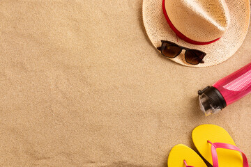 Wall Mural - Summer vacation composition. Flip flops, hat and other stuff on sand background