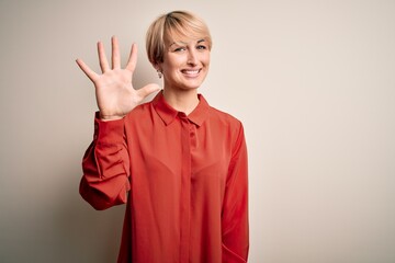 Sticker - Young beautiful business blonde woman with short hair standing over isolated background showing and pointing up with fingers number five while smiling confident and happy.