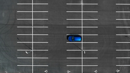 Top view on an empty parking lots with one blue car. Aerial view of car park.