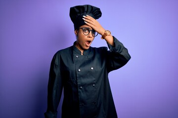 Sticker - Young african american chef girl wearing cooker uniform and hat over purple background surprised with hand on head for mistake, remember error. Forgot, bad memory concept.