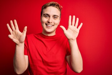 Wall Mural - Young handsome redhead man wearing casual t-shirt over isolated red background showing and pointing up with fingers number nine while smiling confident and happy.