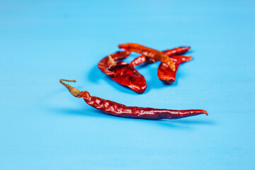 Wall Mural - Dried red chili peppers and chili powder spice on blue background
