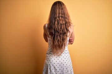 Sticker - Young beautiful blonde woman on vacation wearing summer dress over yellow background standing backwards looking away with crossed arms