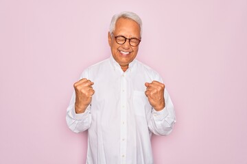 Poster - Middle age senior grey-haired man wearing glasses and business shirt over pink background very happy and excited doing winner gesture with arms raised, smiling and screaming for success. Celebration