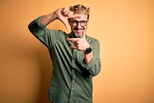 Middle Age Hoary Man Wearing King Crown Standing Over Isolated Yellow Background Smiling Making Frame With Hands And Fingers With Happy Face. Creativity And Photography Concept.