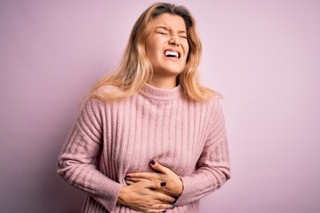 Canvas Print - Young beautiful blonde woman wearing casual pink sweater over isolated background with hand on stomach because nausea, painful disease feeling unwell. Ache concept.