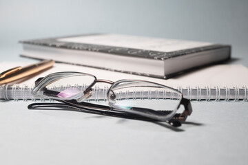 Poster - Glasses golden pen notebook planner in office business or education composition in white black golden blue colors