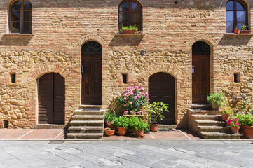 Wall Mural - Sunny streets with colorful flowers with contrasting shades. Walk the Tuscan town