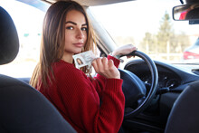 Joyful Girl Driving A Training Car With A Drivers License Card In Her Hands