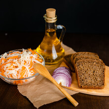 Three Jars Of Sauerkraut And Carrots In Its Own Juice With Spices And A Bottle Of Oil, Bread And Onion, White Wooden Table. Traditional Home-made, Fermented Dish Of Russia And Germany