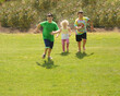 © PhyllisPhotos - Three young children run on a grassy slope.
