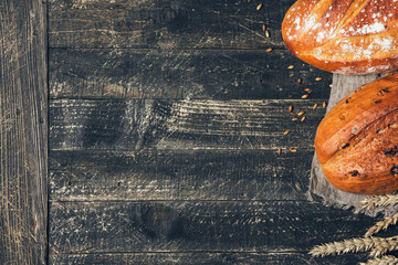 Brown and white breads with spikelets on wooden background with copy space. Two different types of bread. Bakery, cooking and grocery store concept.