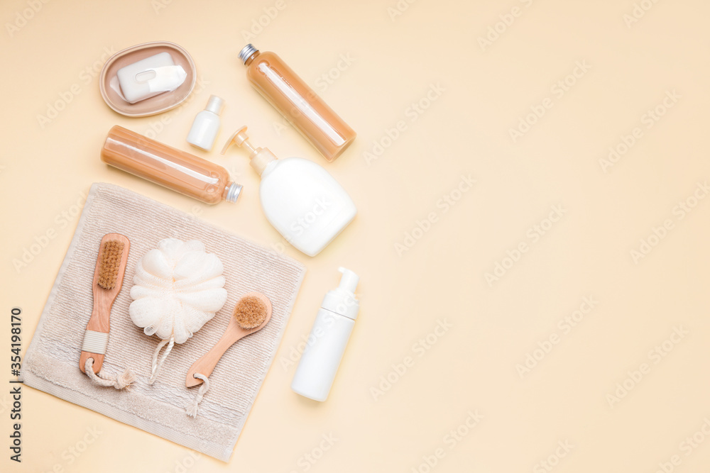 Shower gels with bath supplies on color background