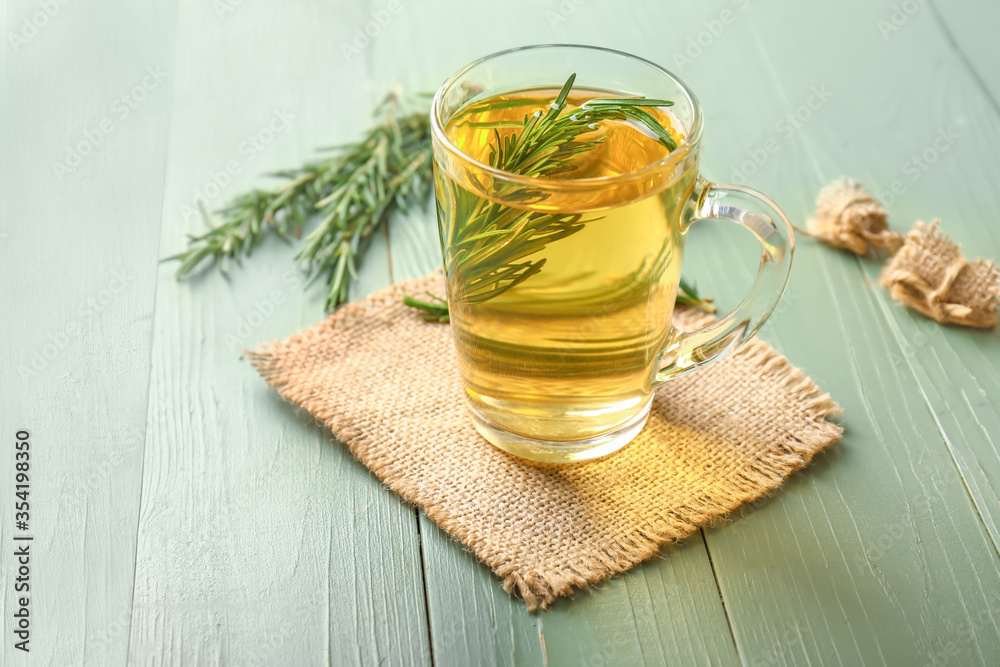 Cup of hot tea with rosemary on table