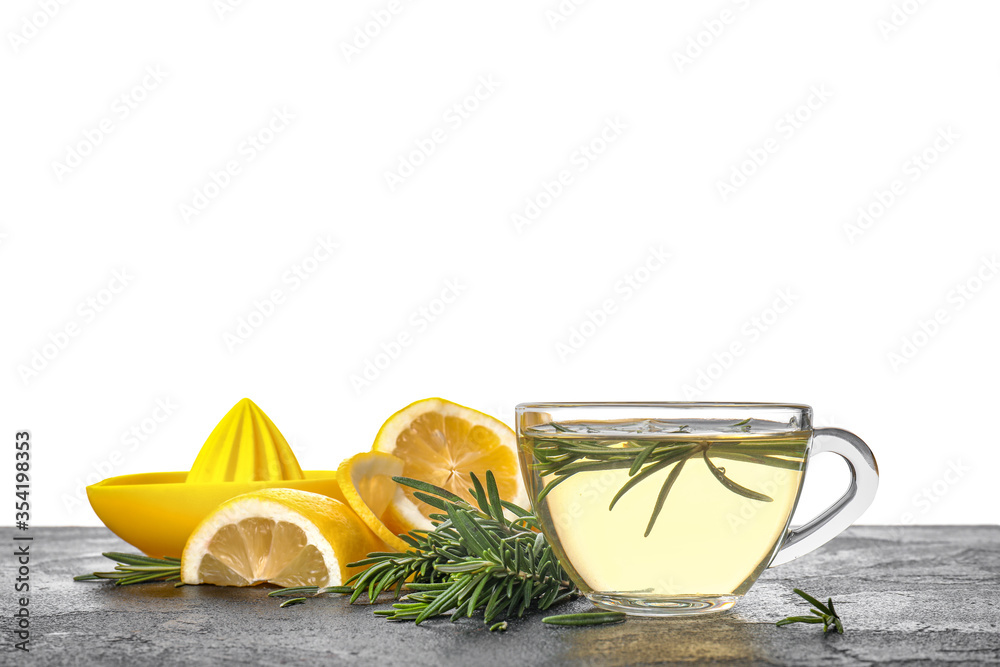 Cup of hot tea with rosemary on table against white background