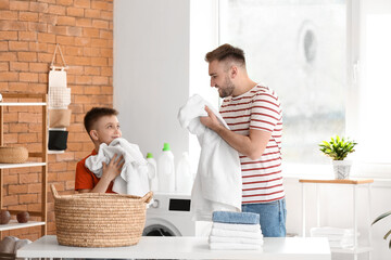 Canvas Print - Man and his little son doing laundry at home