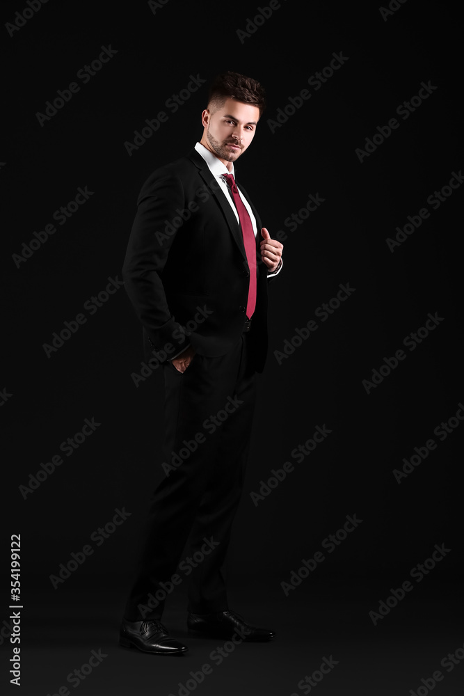 Handsome young man in elegant suit on dark background