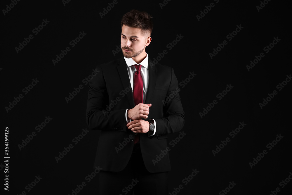 Handsome young man in elegant suit on dark background