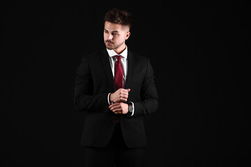 Handsome young man in elegant suit on dark background