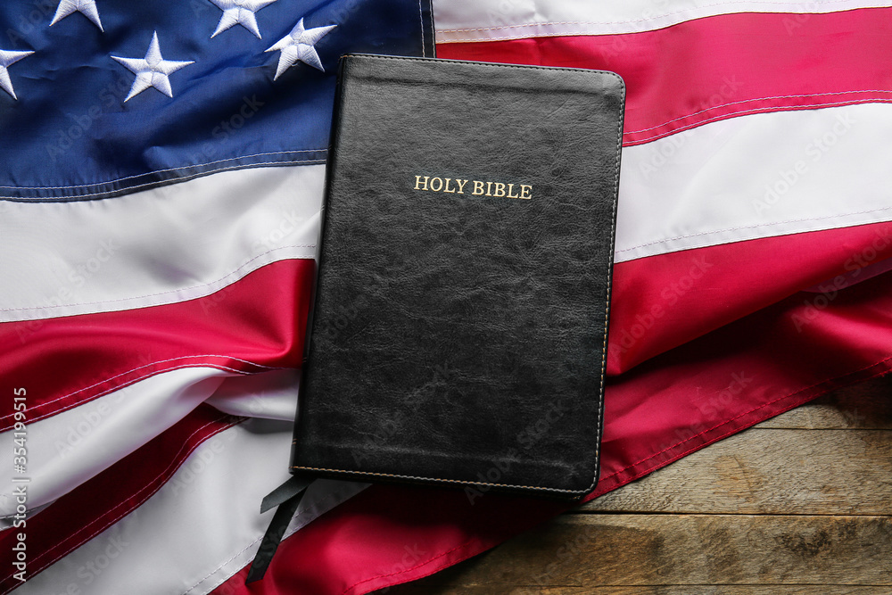 Holy Bible and USA flag on table