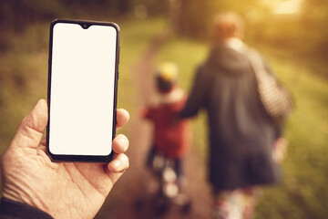 Phone in hand on the background of walking family